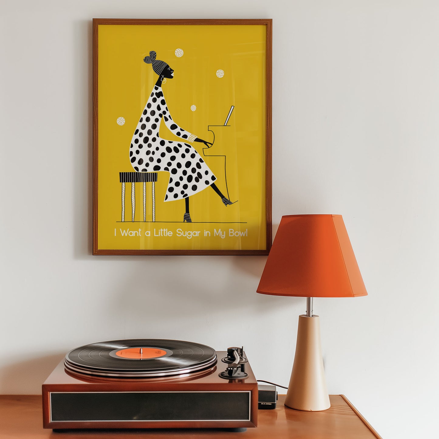 Framed Jazz print artwork of a polka dot dress on a yellow background, placed above a record player with an orange lamp.
