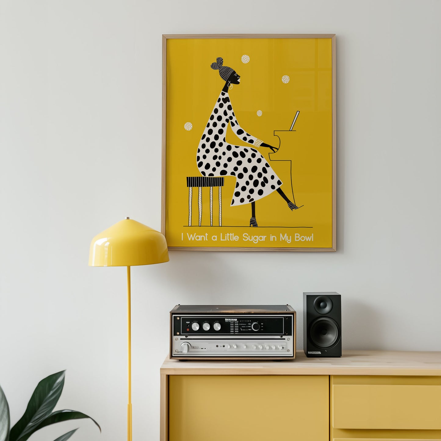 Yellow framed poster with a polka dot giraffe design on a wall above a wooden cabinet with audio equipment.