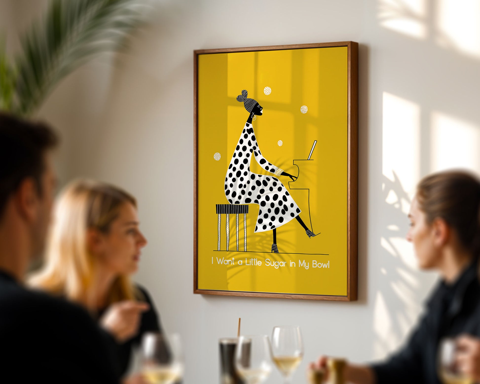 Framed artwork of Nina Simone a polka dot dress on a yellow background, hanging in a room with people socializing.