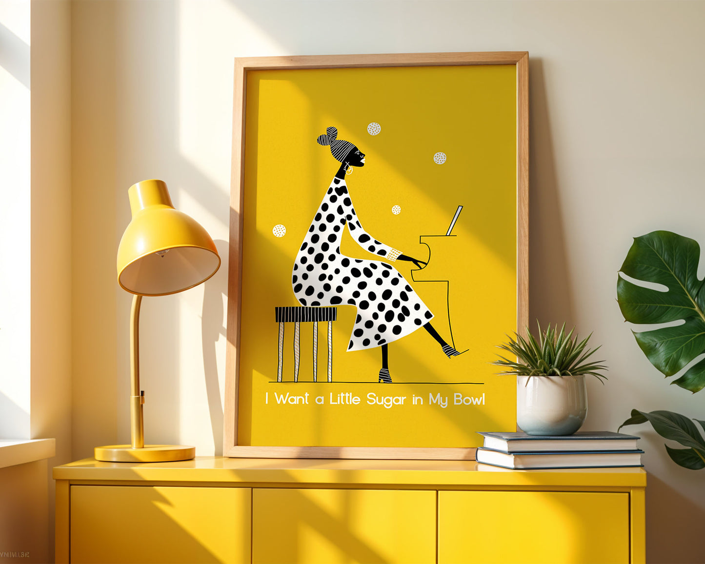 Framed artwork of Nina Simone in a polka dot dress on a yellow background, displayed on a yellow cabinet with a lamp and plant.