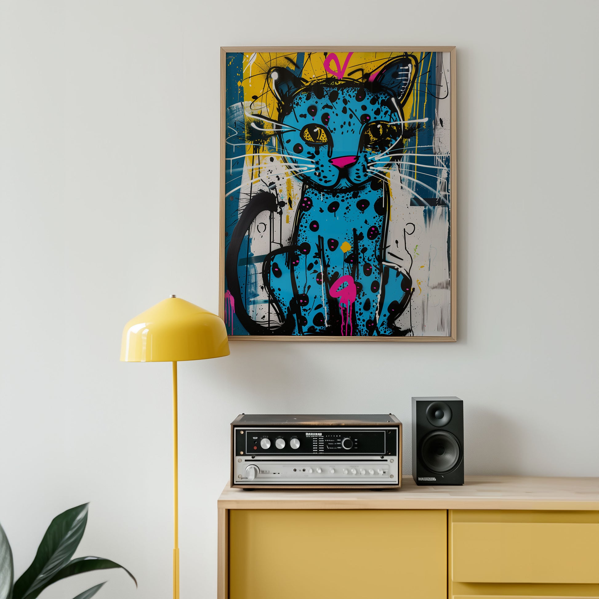 Colorful abstract cat painting on a wall above a yellow cabinet with electronic equipment.