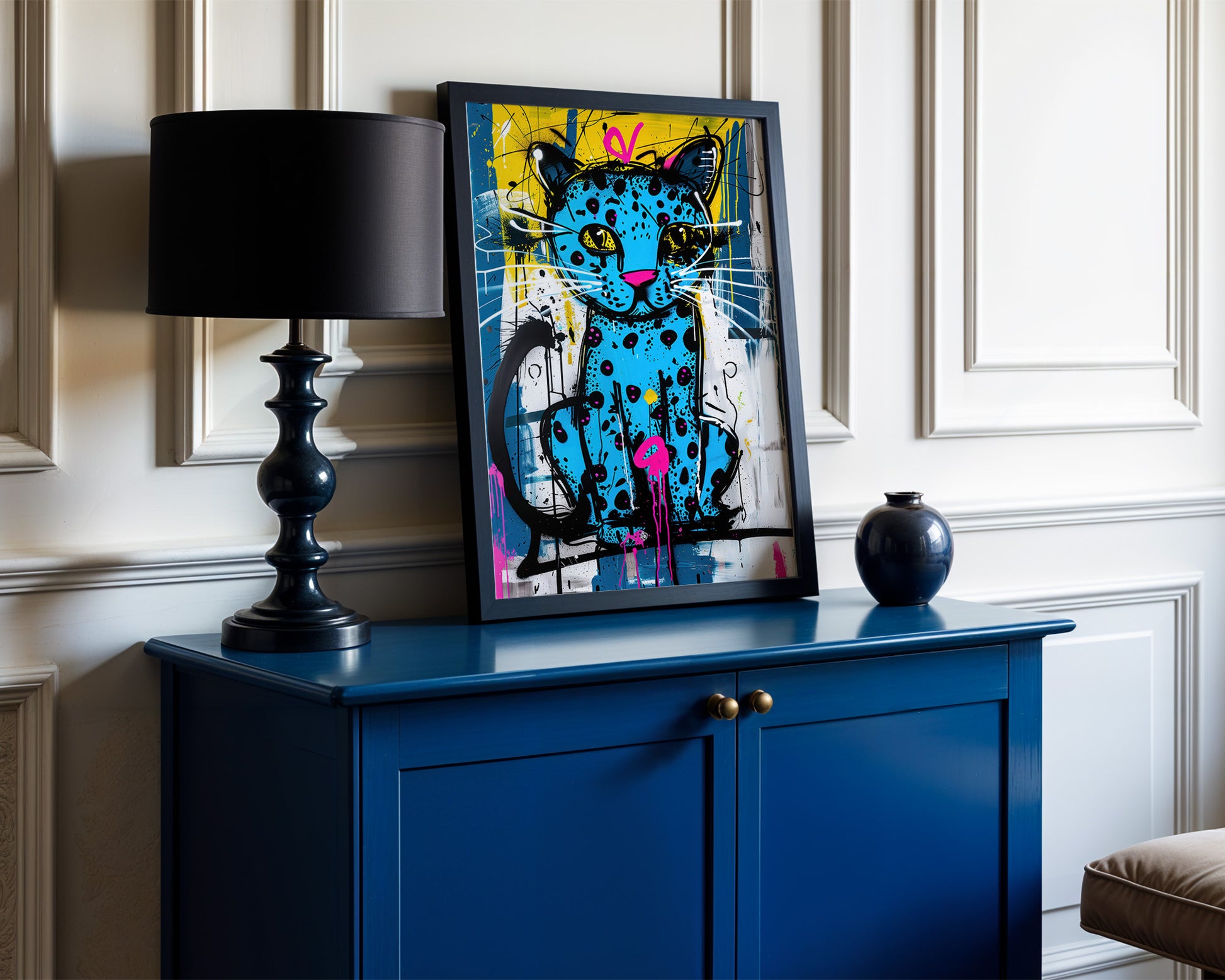 Blue cabinet with an indie wall art cat painting, black lamp, and black vase against a white wall.