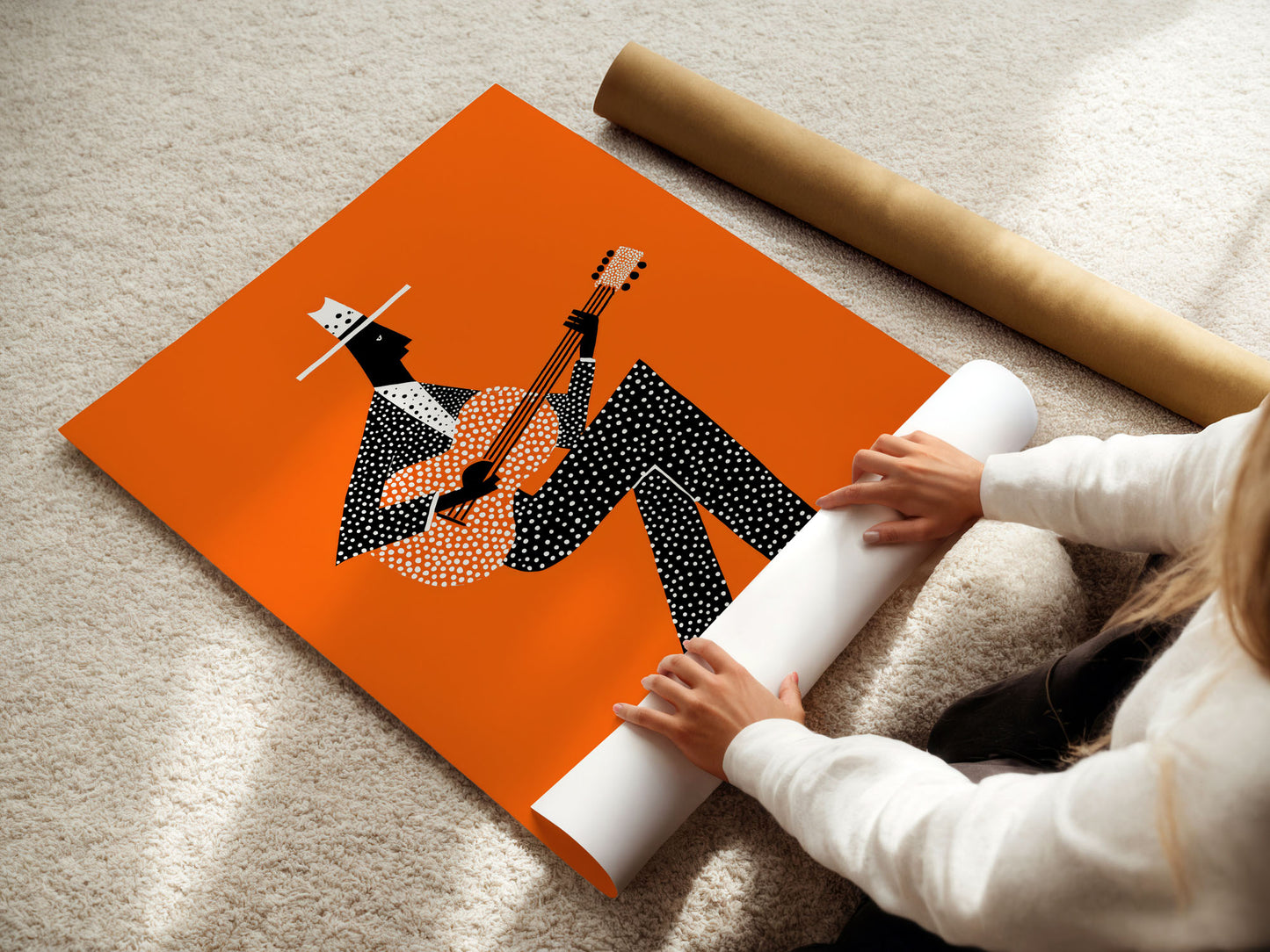 Person unrolling a poster with a design of a person playing a guitar on an orange background.