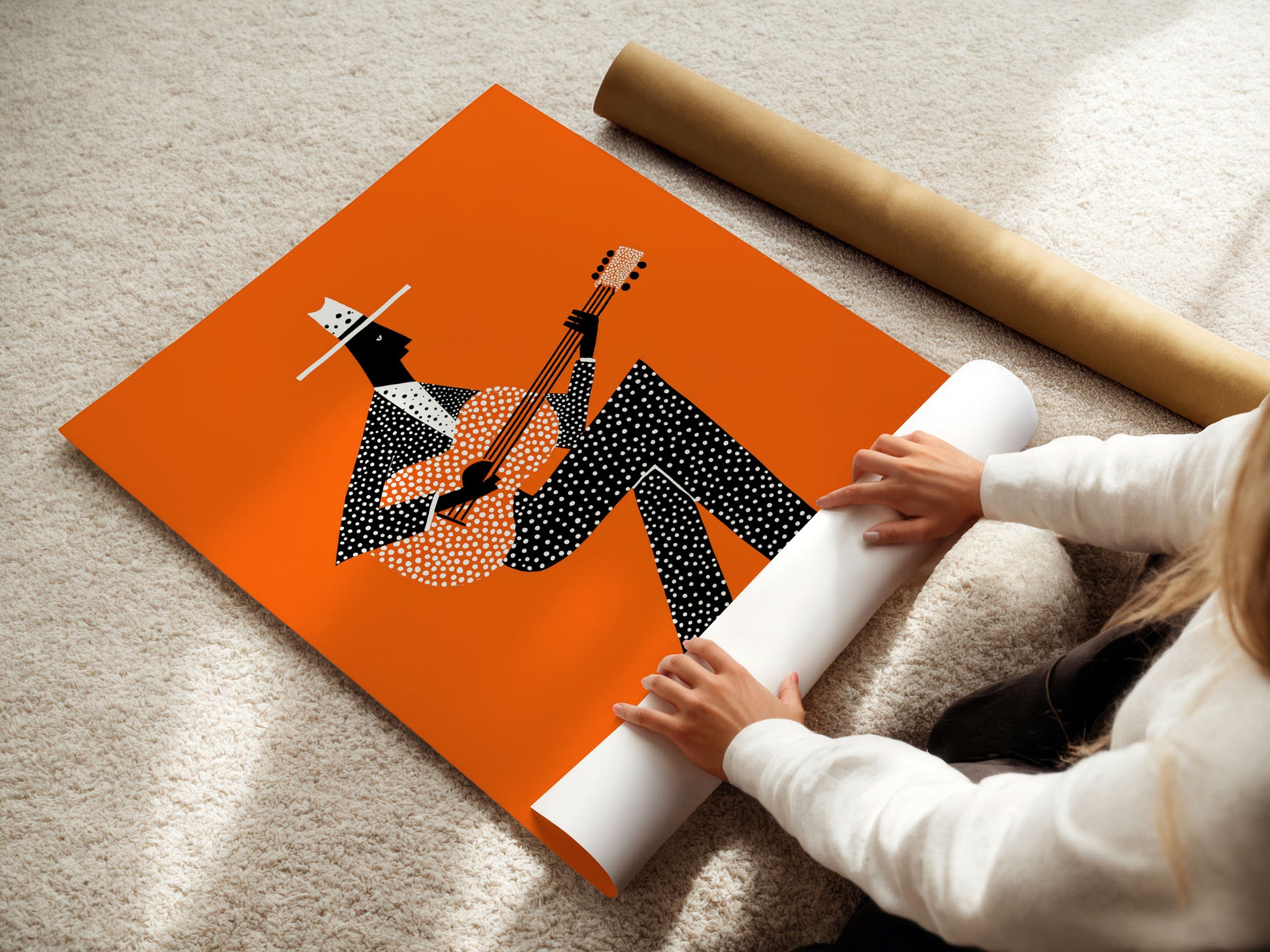 Person unrolling a poster with a design of a person playing a guitar on an orange background.