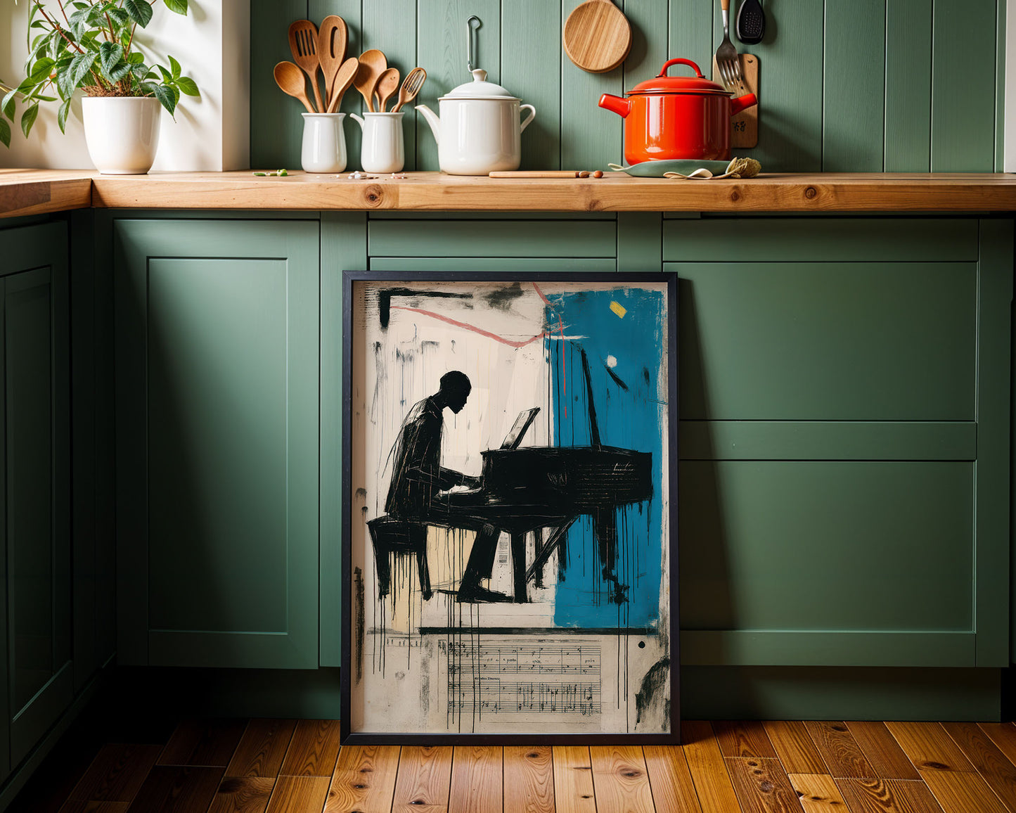 Framed artwork of a person playing a piano in a kitchen setting with green cabinets and wooden countertops.