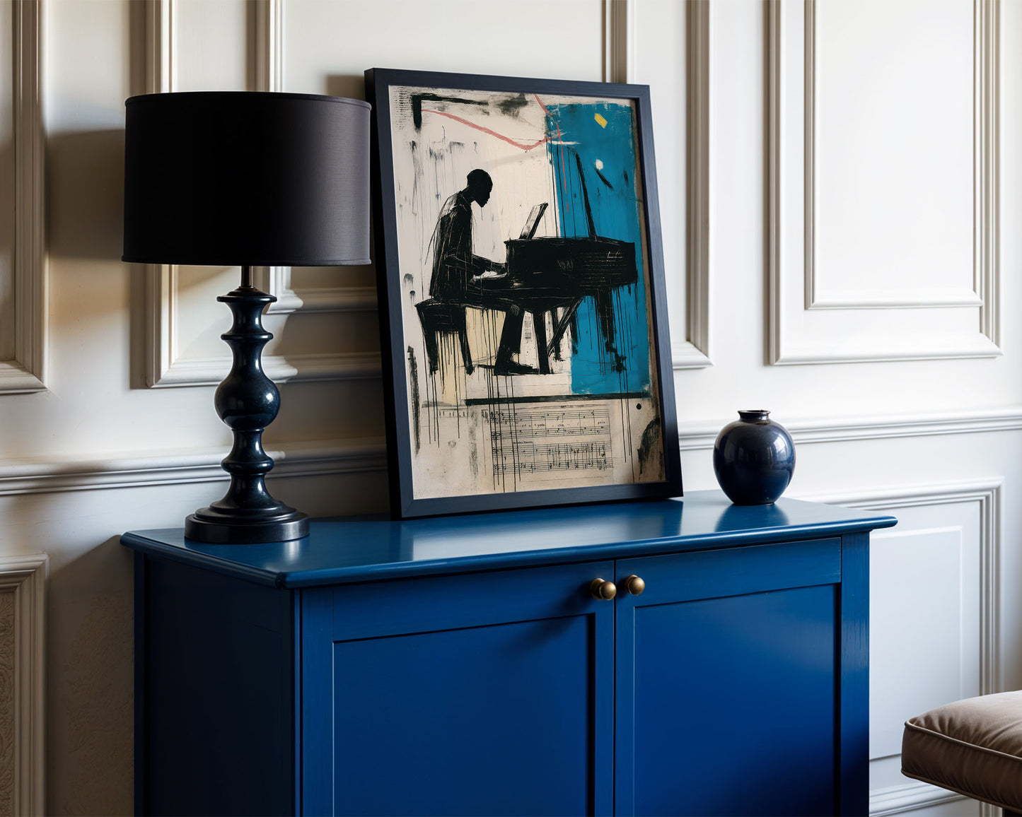 Blue cabinet with a black lamp, framed artwork, and a blue vase against a white wall.