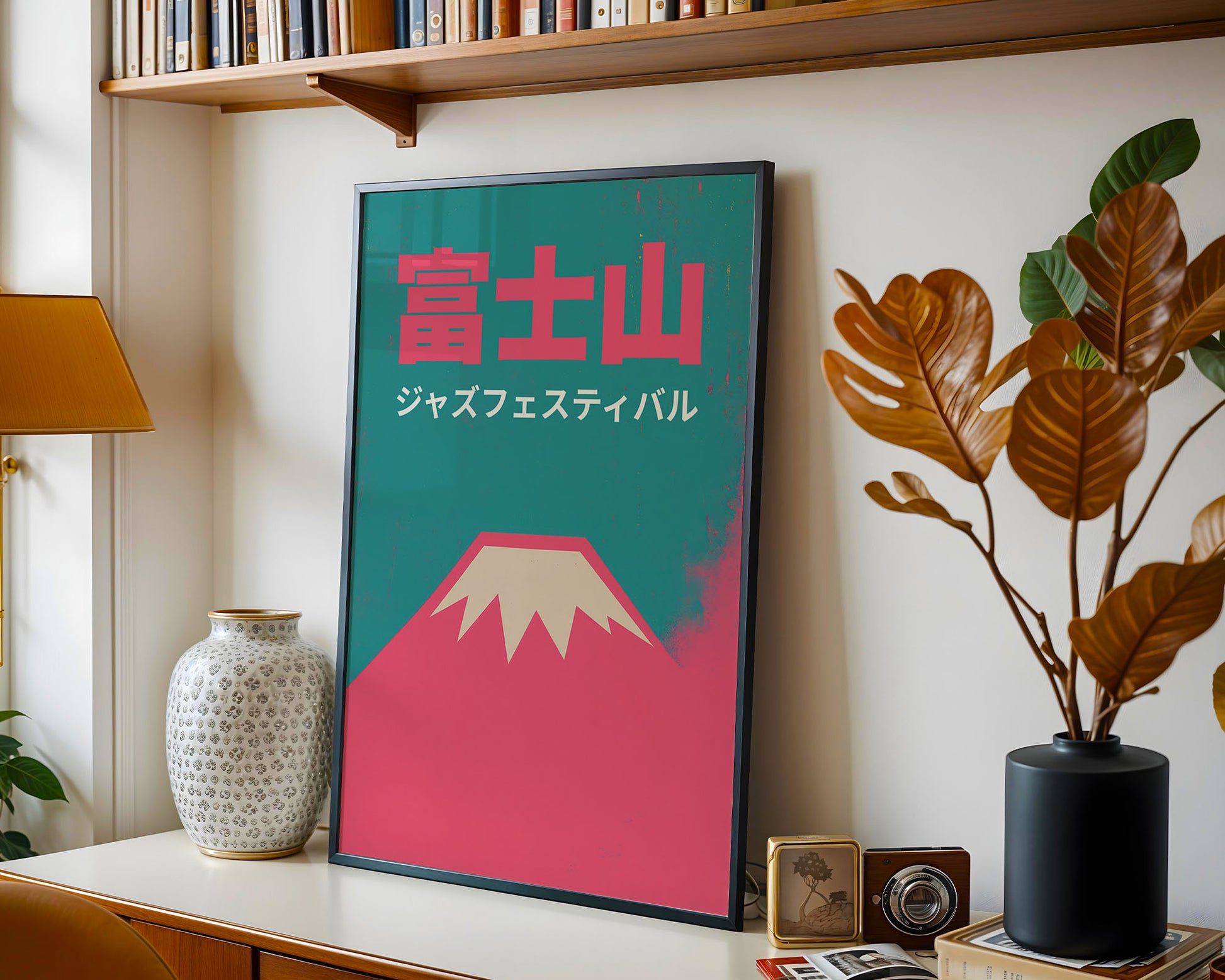 Framed artwork with a mountain design and Japanese text on a shelf with books and decor.