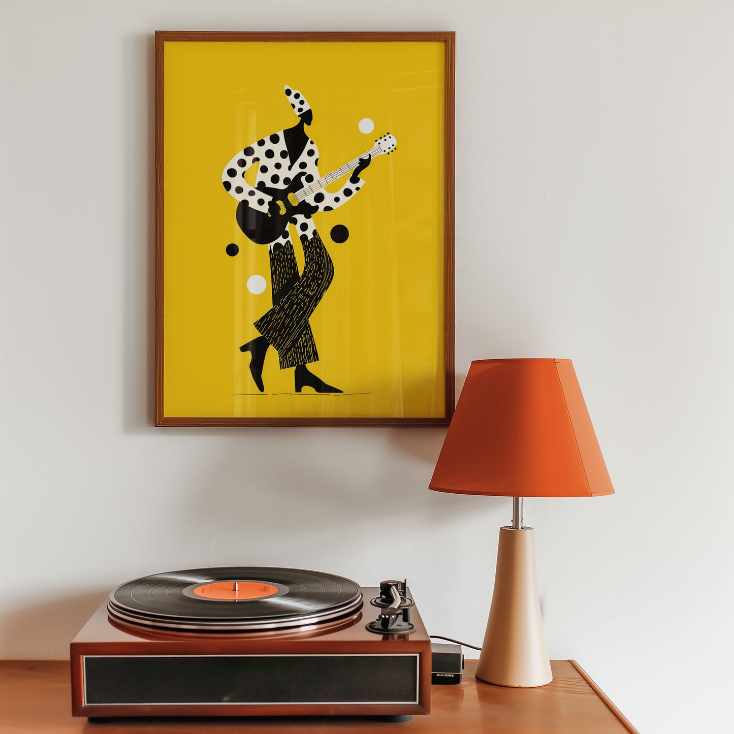 Framed artwork of a dancer on a yellow background above a record player with an orange lamp.