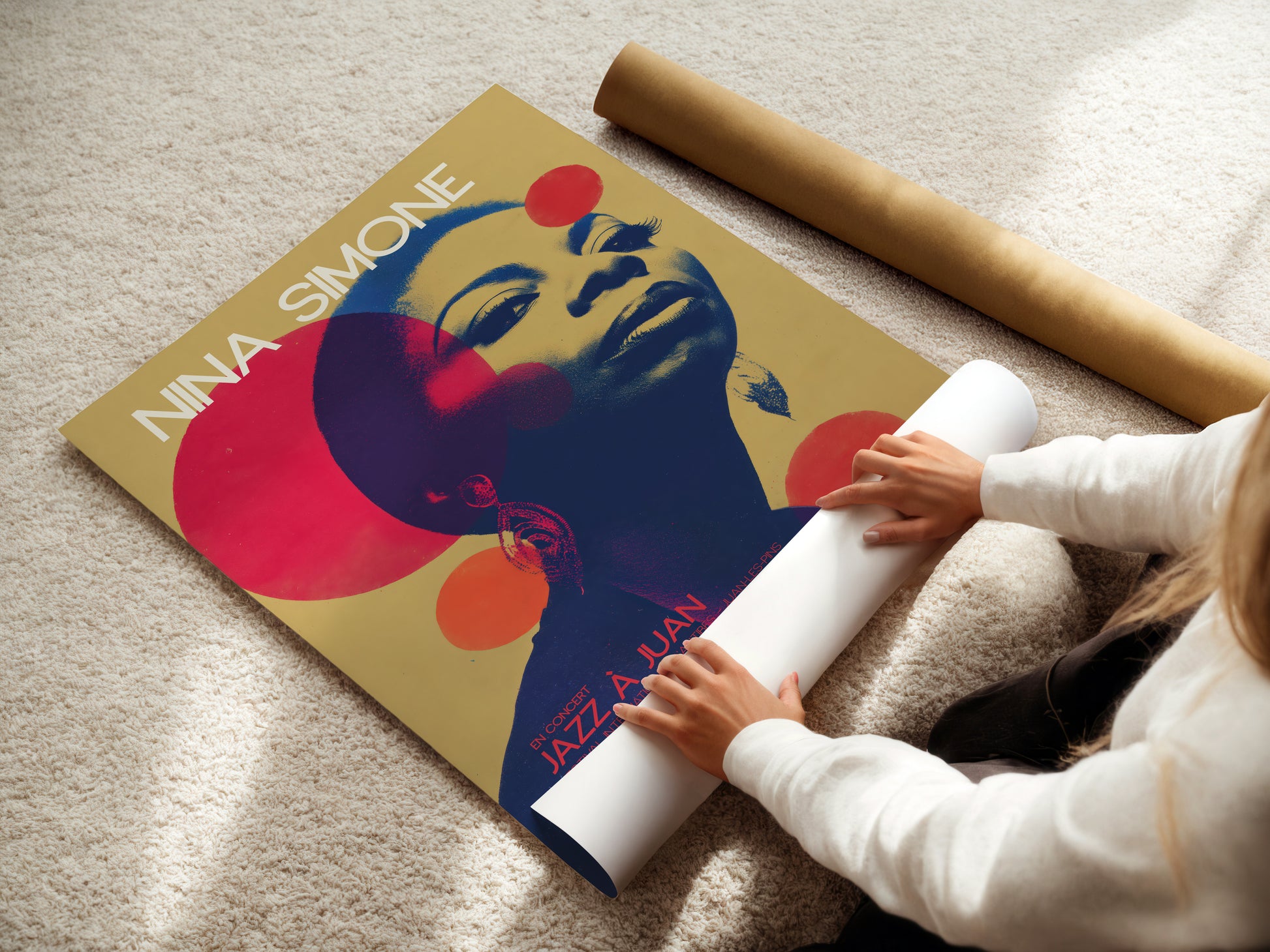 Person unrolling a poster of Nina Simone on a carpeted floor