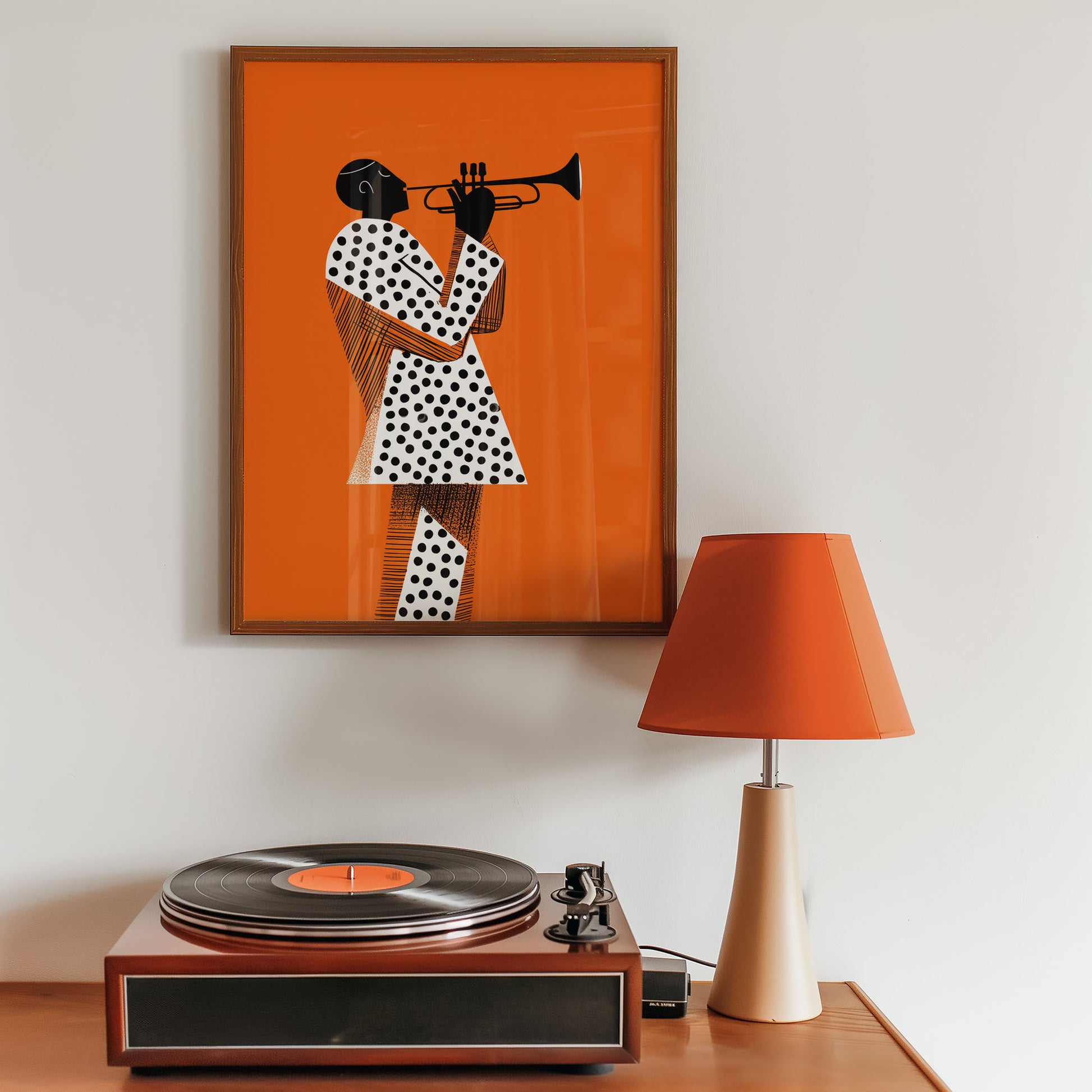 Framed mid-century style wall art print of a person playing a trumpet on an orange background, placed above a record player with a lamp beside it.