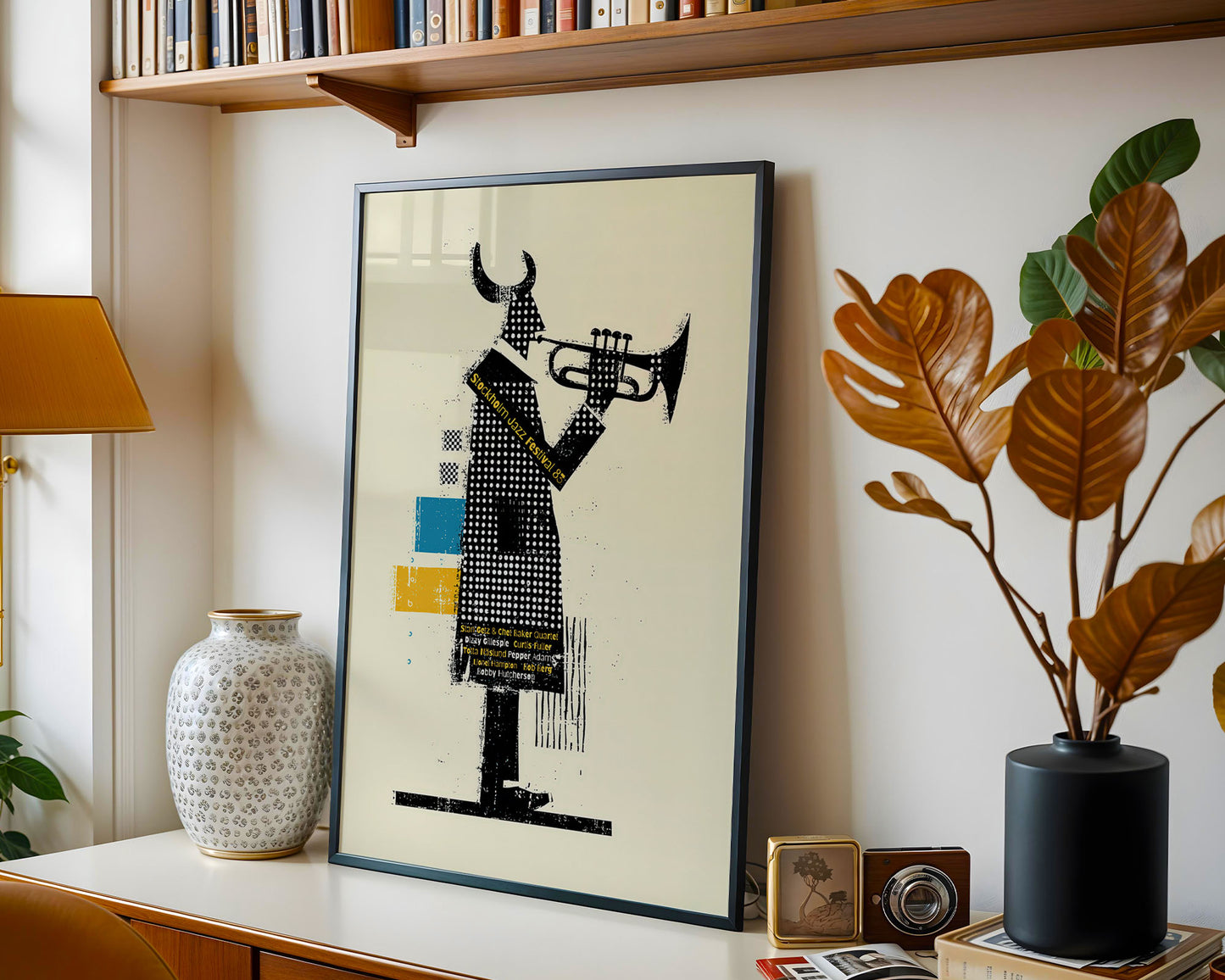 Framed artwork on a shelf with decorative items including a lamp, vase, and plant.