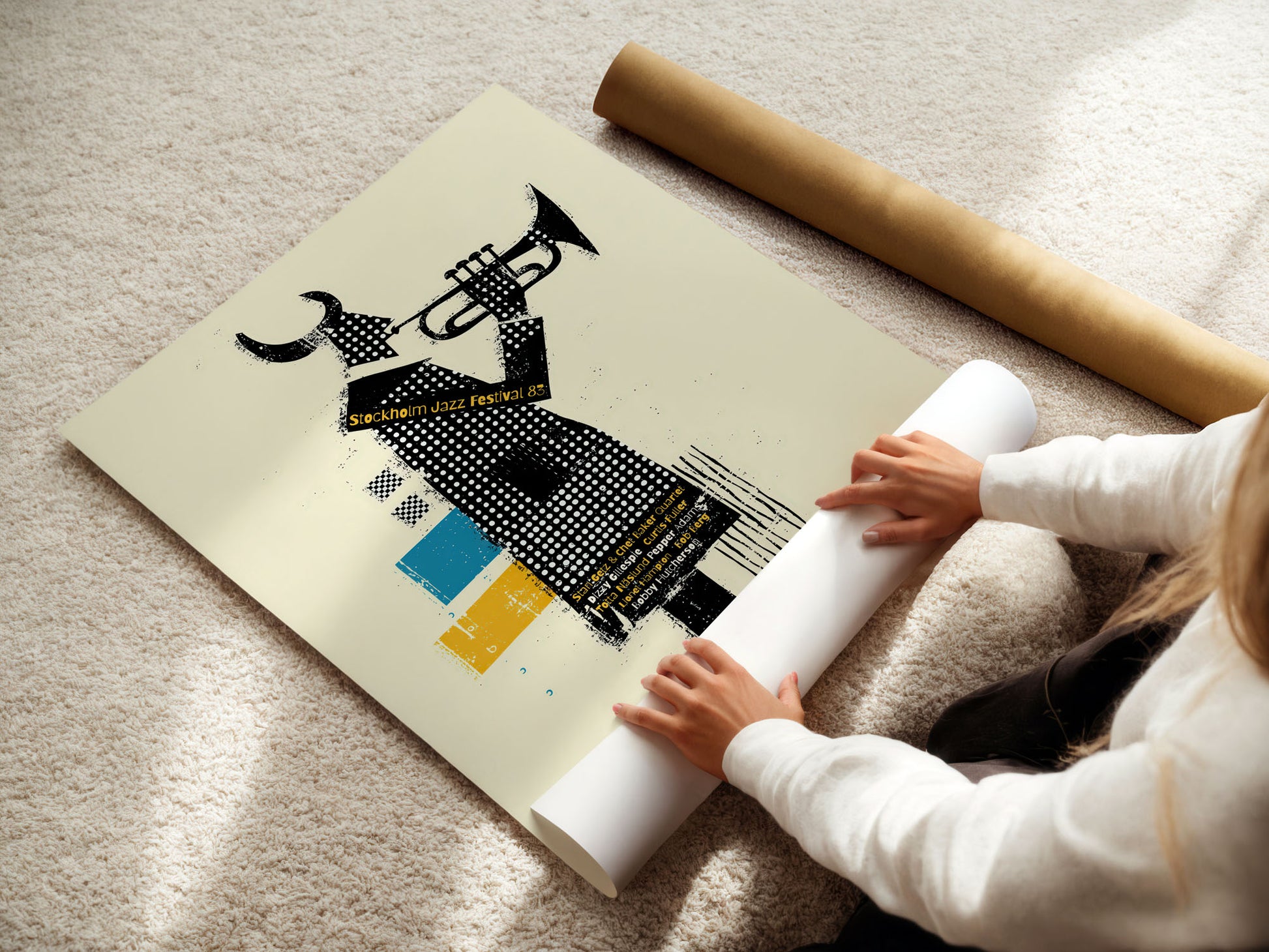 Person unrolling a large poster with artistic design on a light-colored floor.