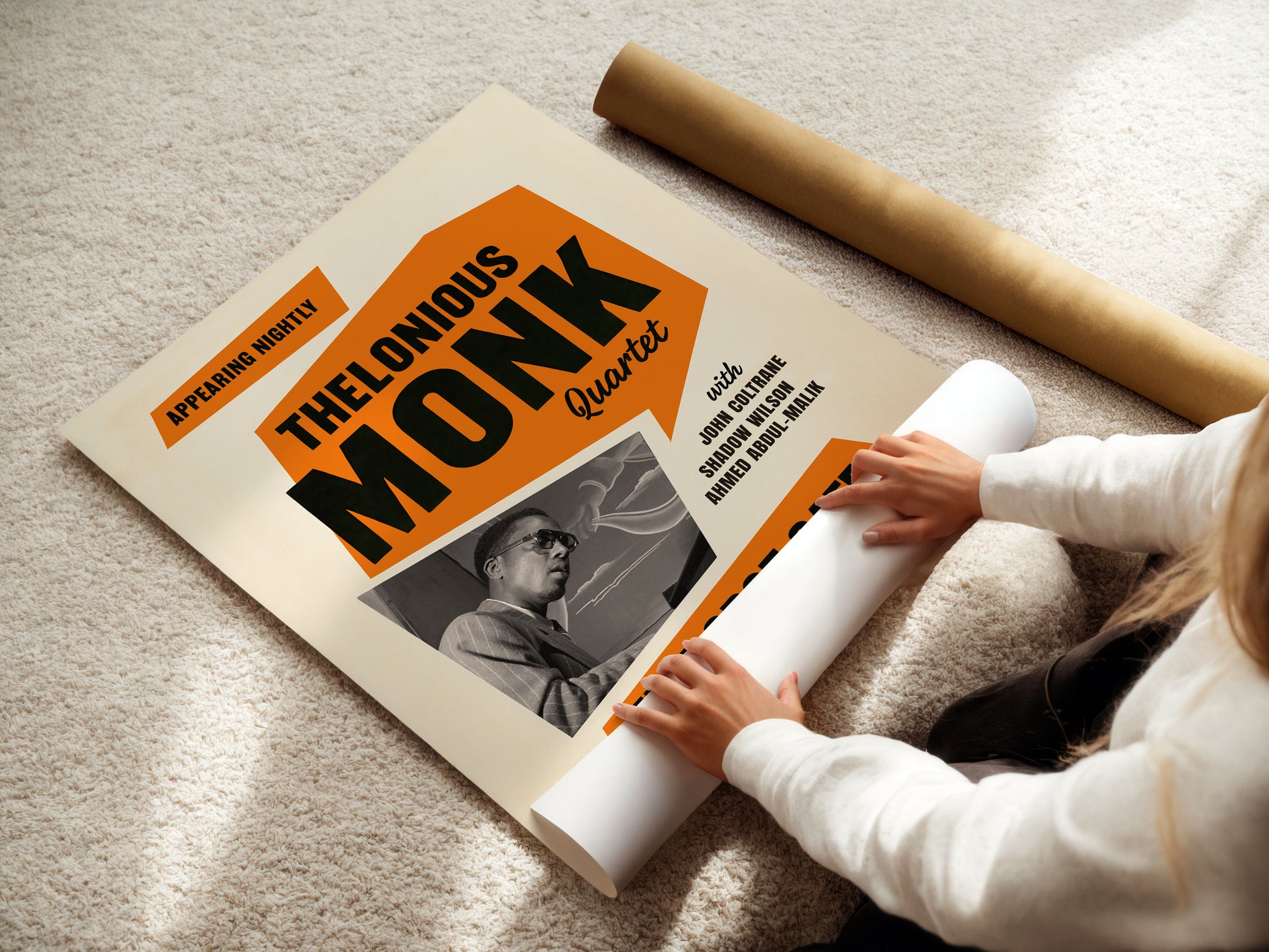 Person unrolling a poster of Thelonious Monk Quartet on a carpeted floor