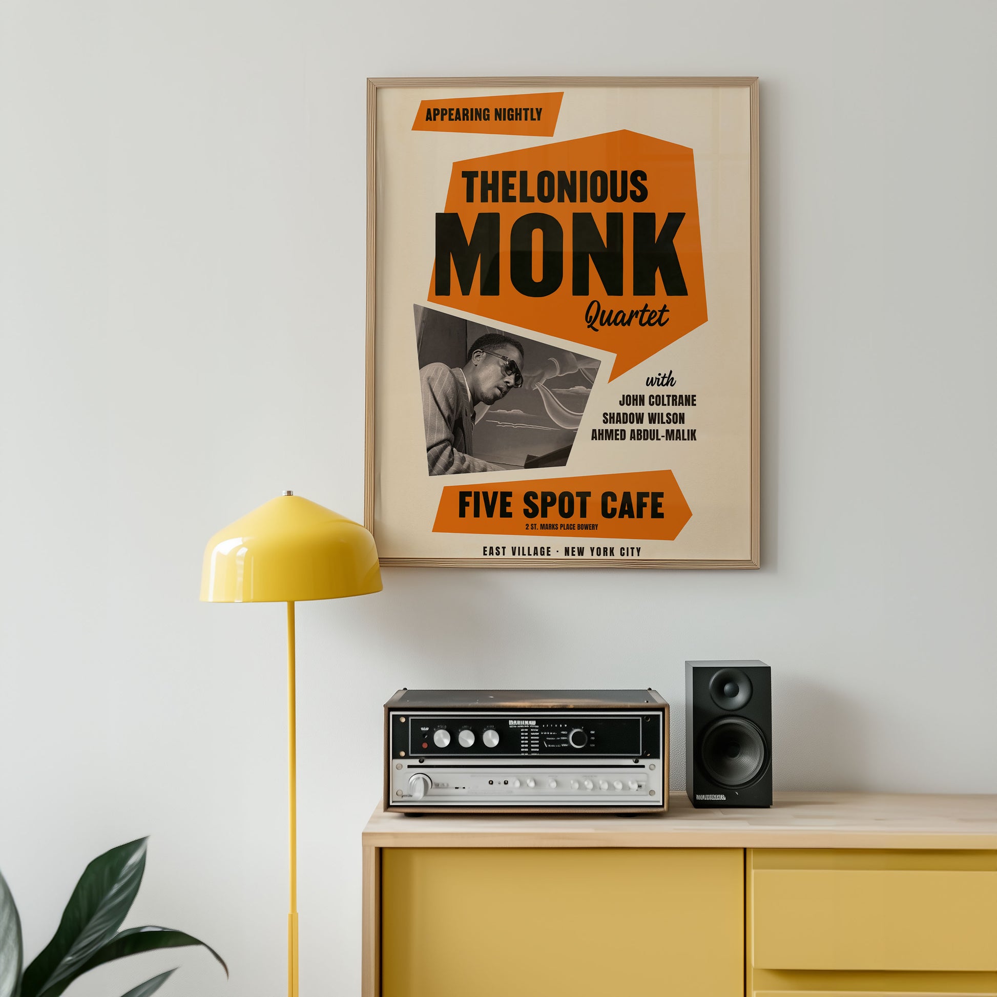 Framed poster of Thelonious Monk Quartet at Five Spot Cafe on a wall above a yellow cabinet with audio equipment.