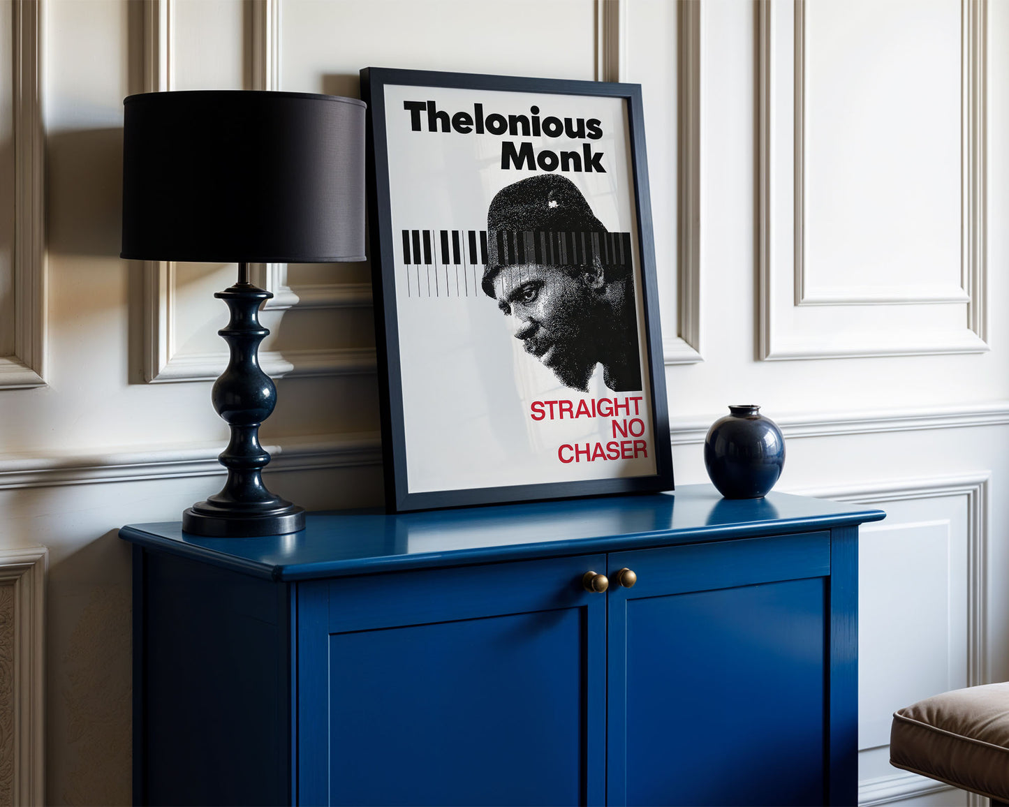 Framed Thelonious Monk poster on a blue cabinet with a black lamp and decorative vase.