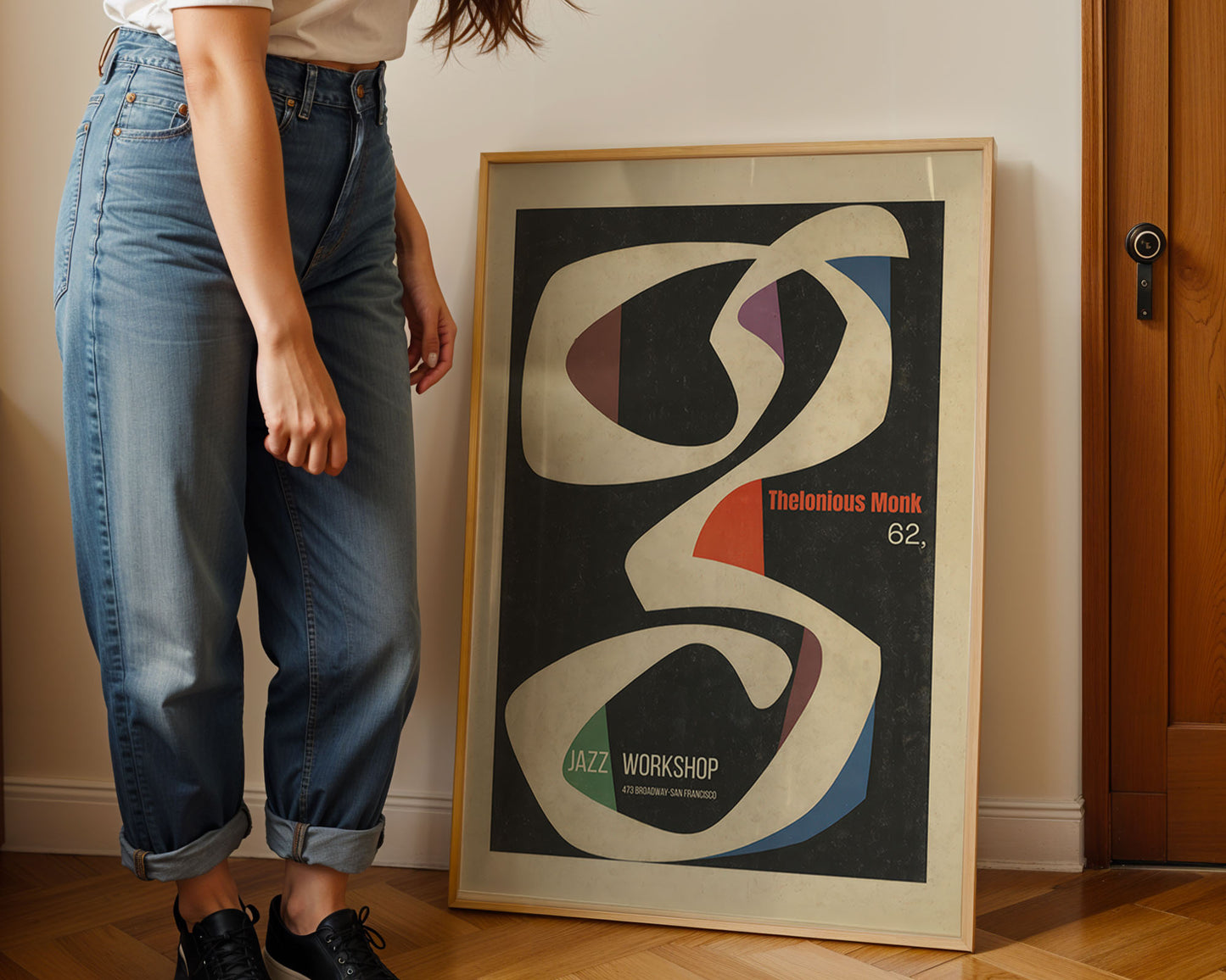 Person standing next to a framed abstract art print on a wall.