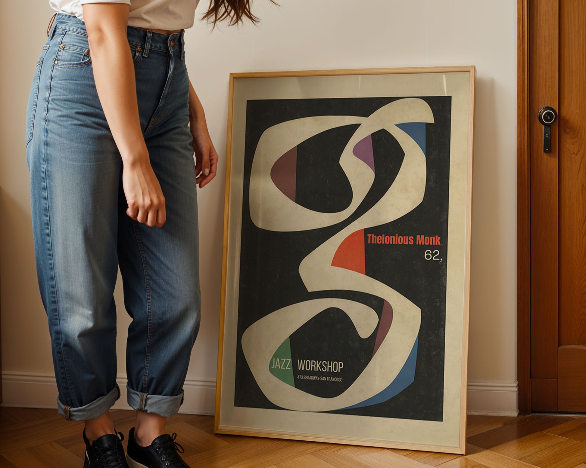 Person standing next to a framed abstract art print on a wall.