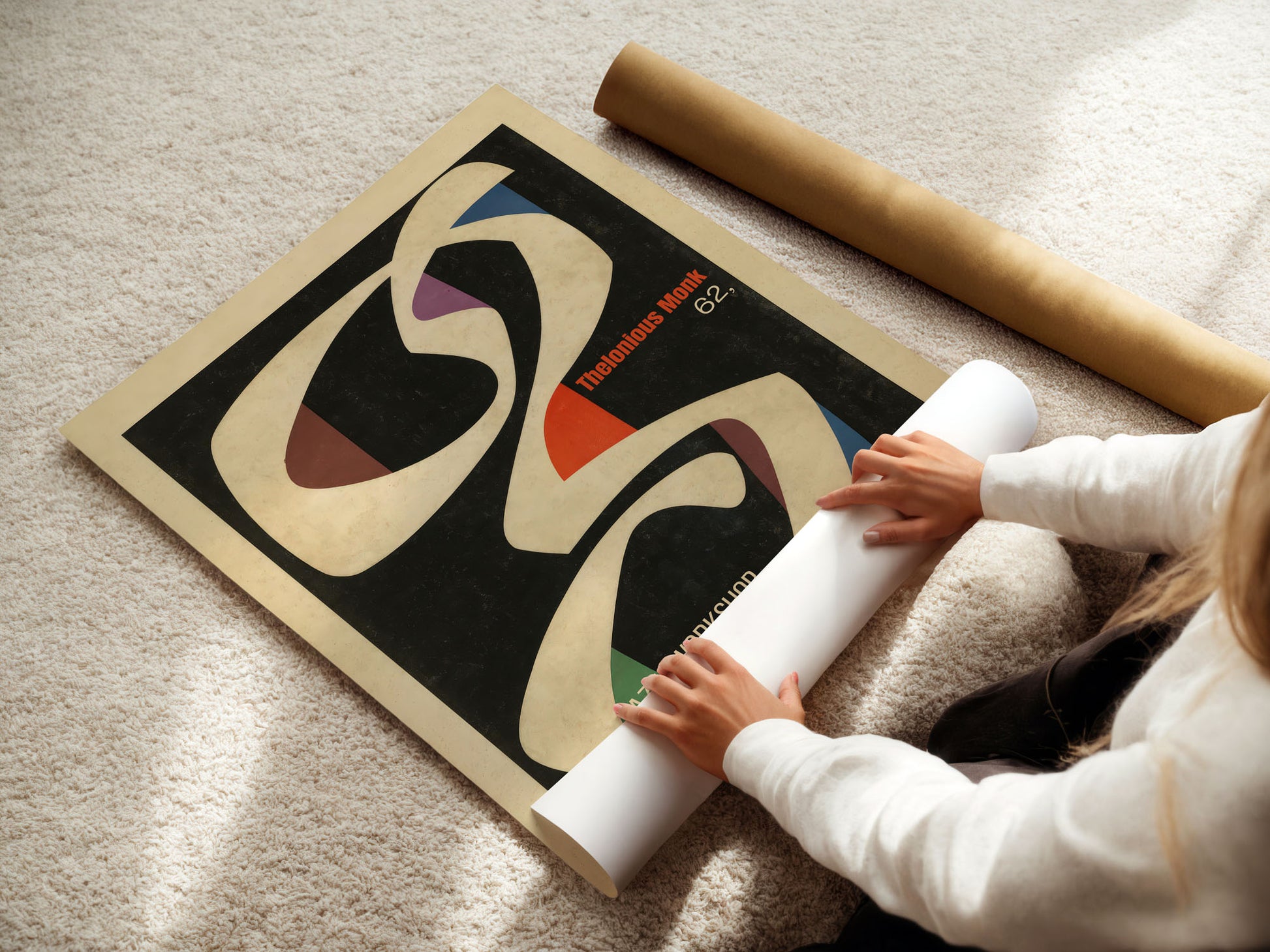 Person unrolling a large abstract art print on a carpeted floor